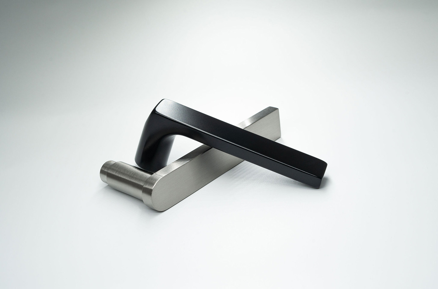 Modern door handle design in matte black and brushed silver, presented on a light, minimalist background.